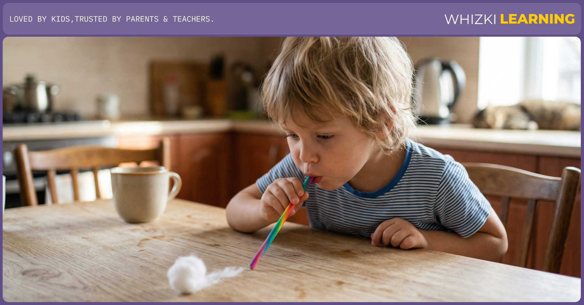 A close-up of a preschooler using a reusable straw to push a soft cotton ball across a table, aiding in concentration.