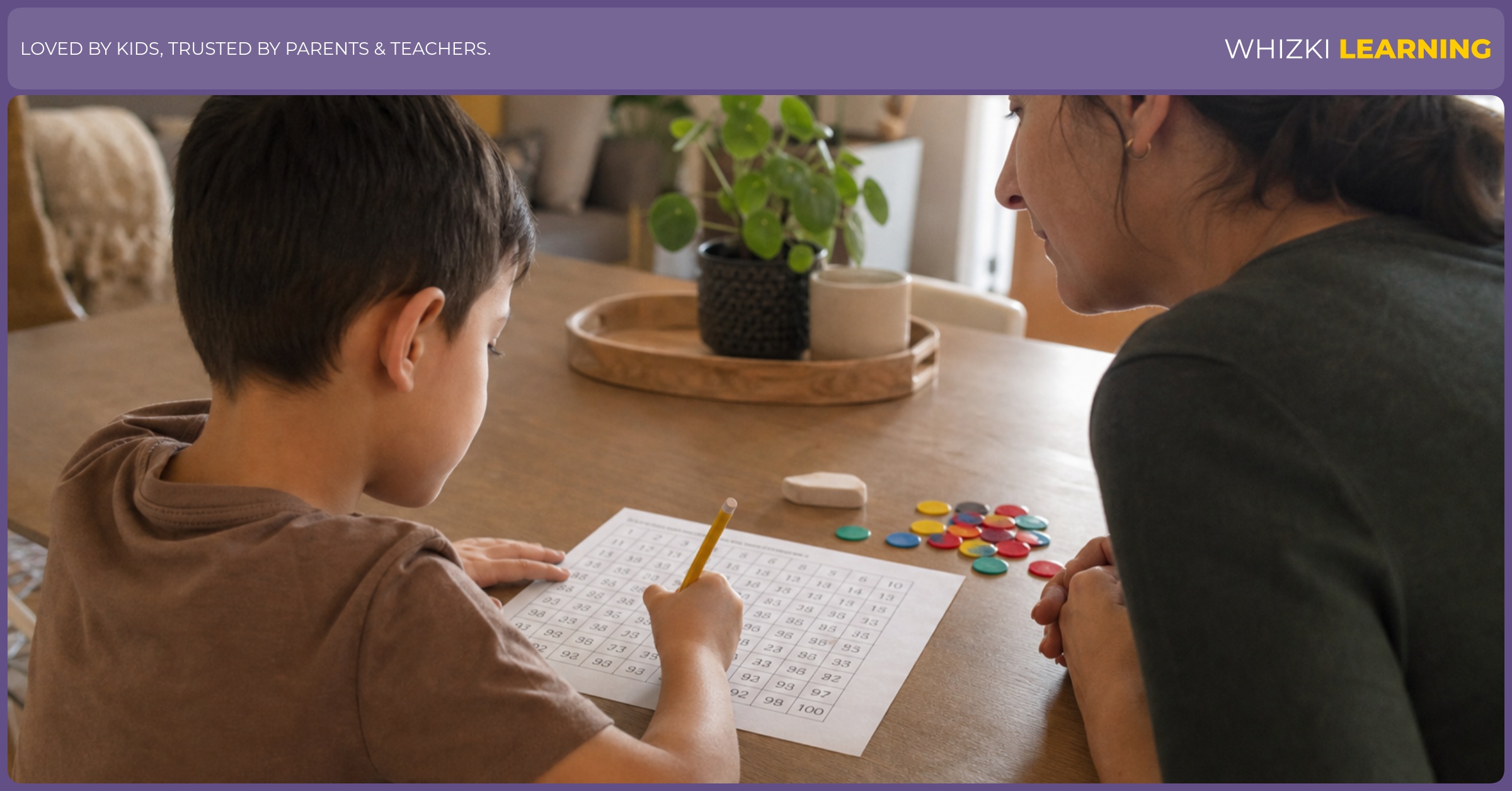 A child writes numbers on a blank 100 chart while a caregiver supports the work with counters nearby.