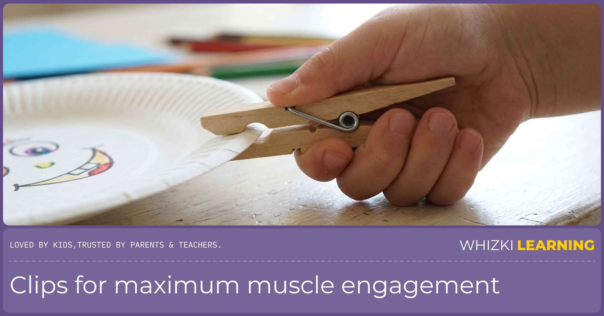 A preschooler's hand strongly gripping a wooden clothespin, pushing it open to attach it to a colorful cardboard circle.