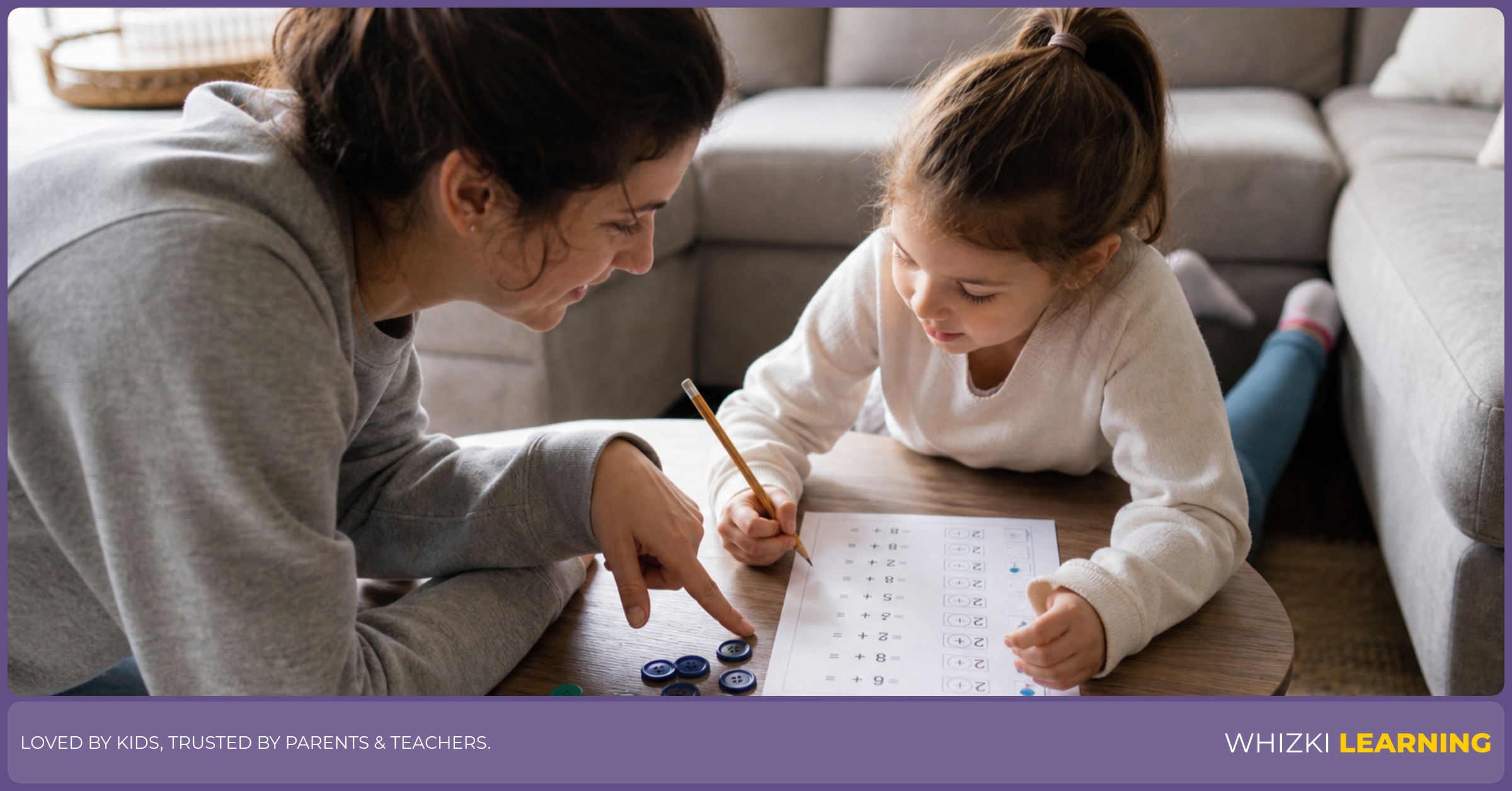 A caregiver points near buttons while a child uses a pencil on an addition to 10 worksheet in a sunny living room.