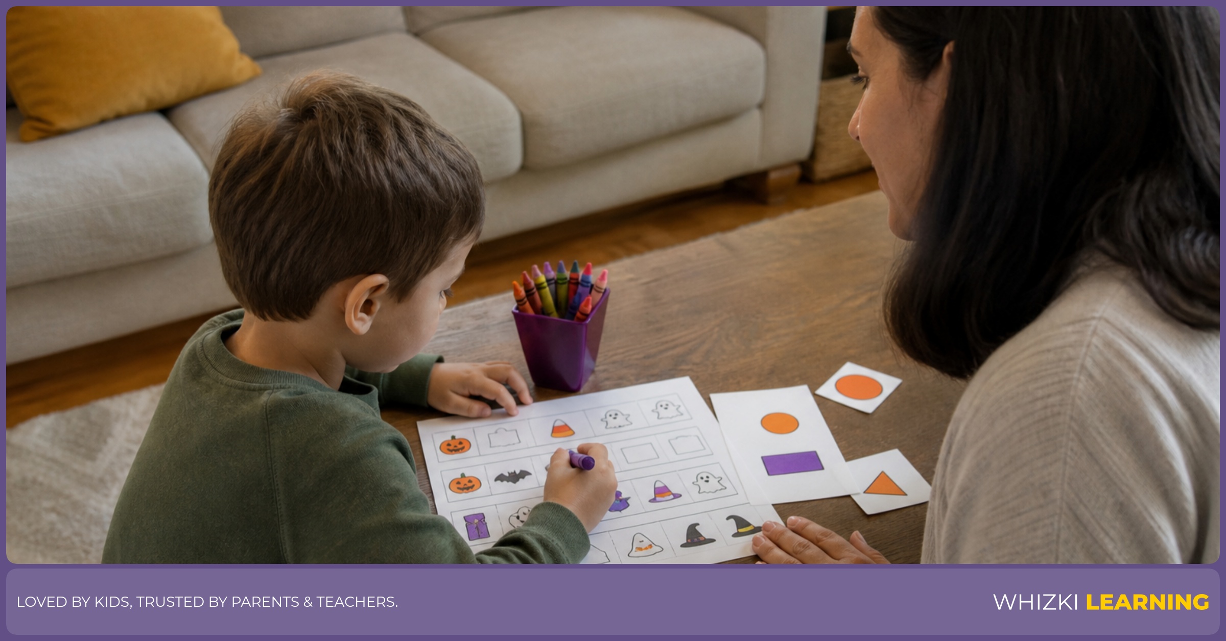 A caregiver sits beside a child completing Halloween picture patterns and shape spotting on a worksheet.