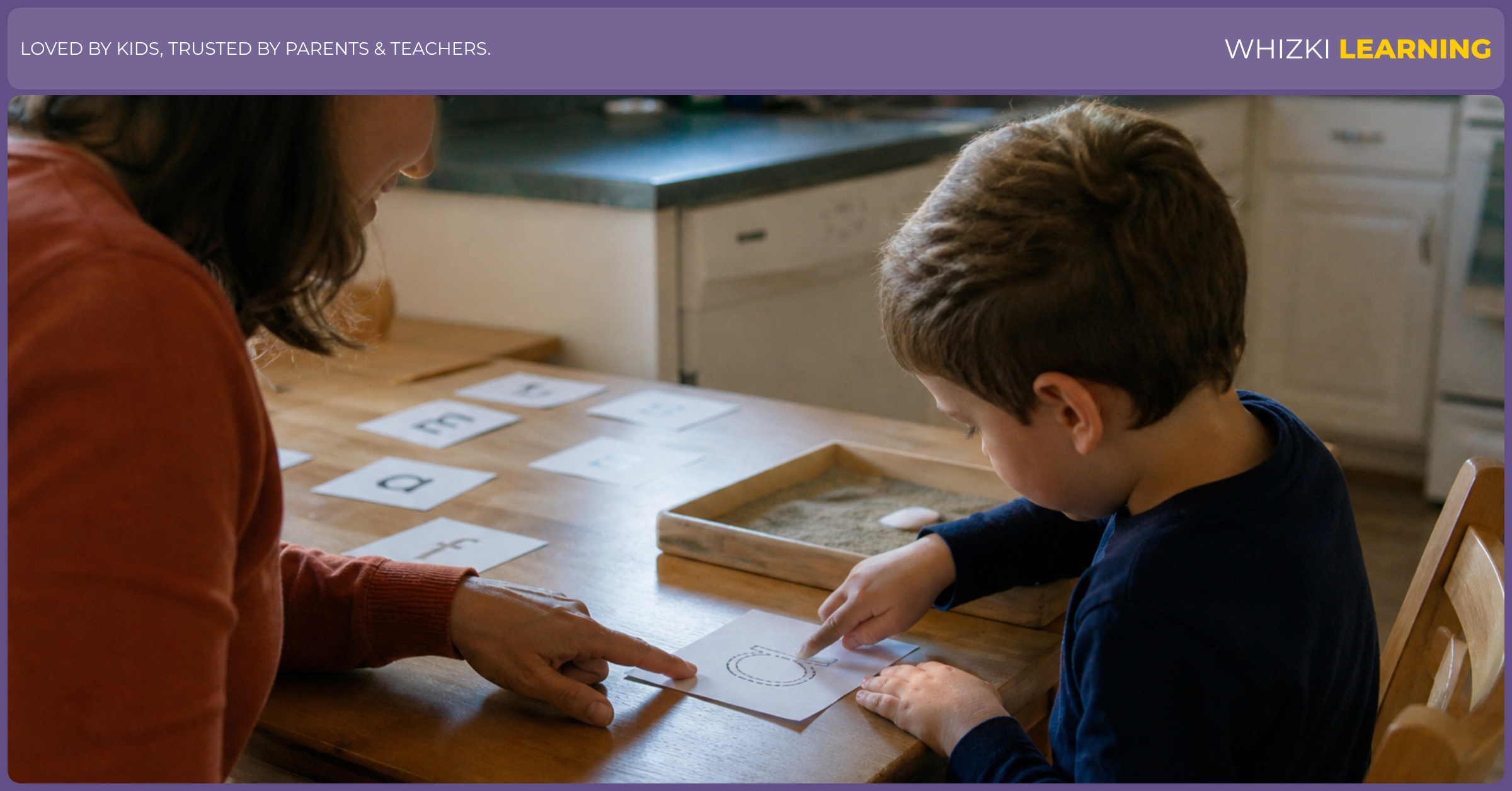 A parent and young child sit at a kitchen table practicing letter sounds with paper cards and a pencil nearby.