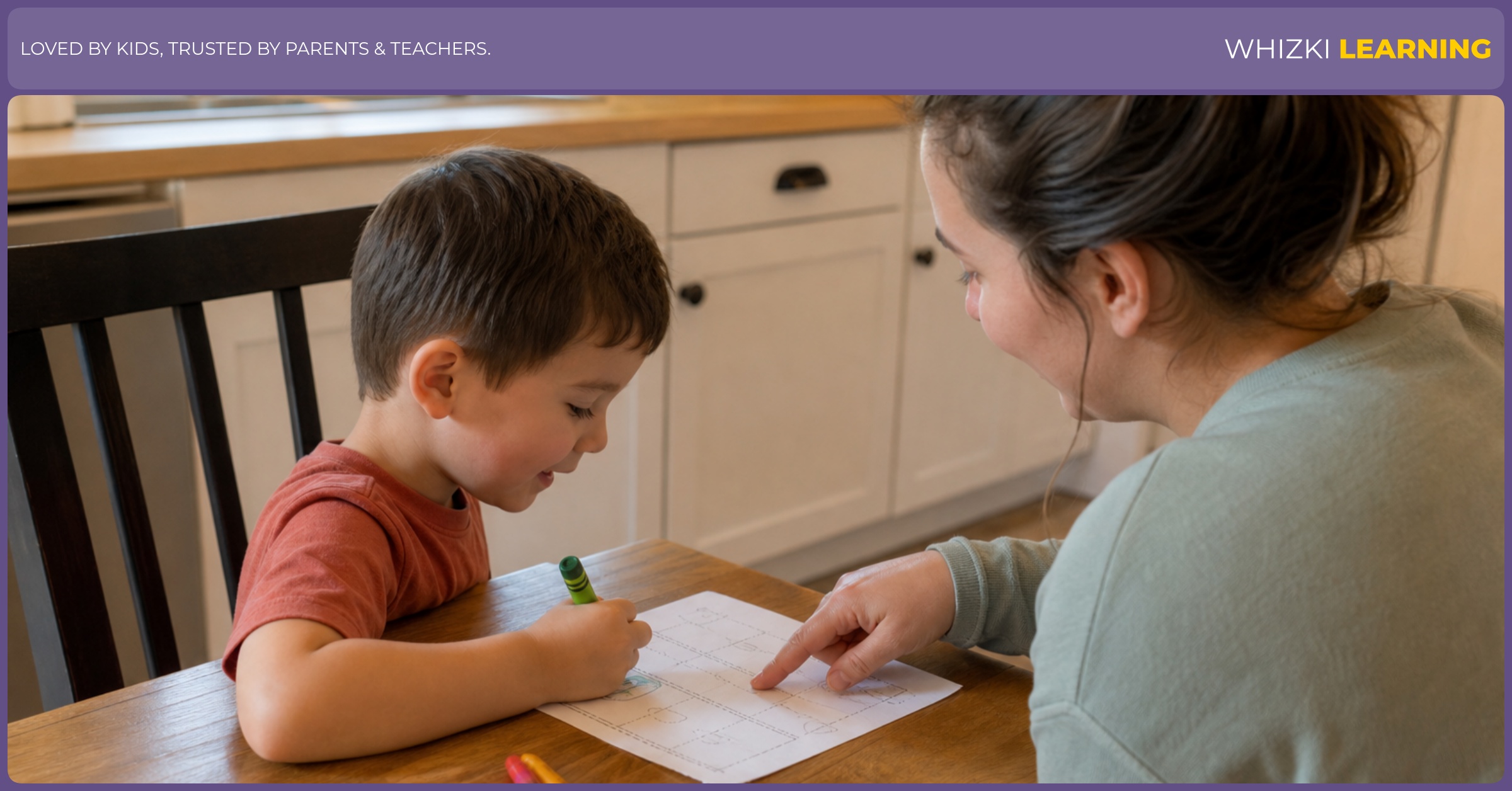 A caregiver sits beside a 5-year-old at a kitchen table while the child traces on paper with crayons nearby.
