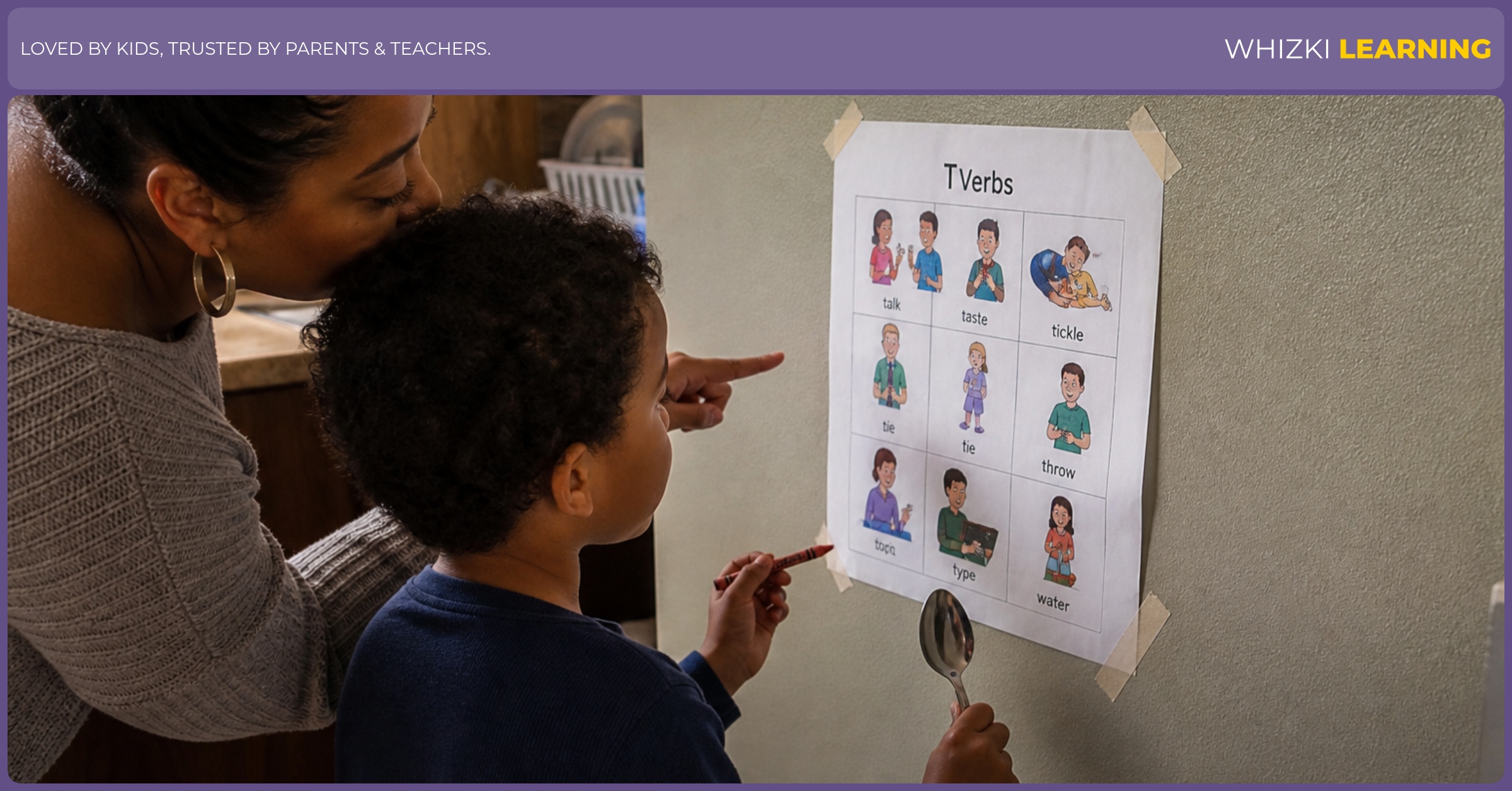 A caregiver points to a T verbs printable taped near the kitchen table while a child holds a crayon.