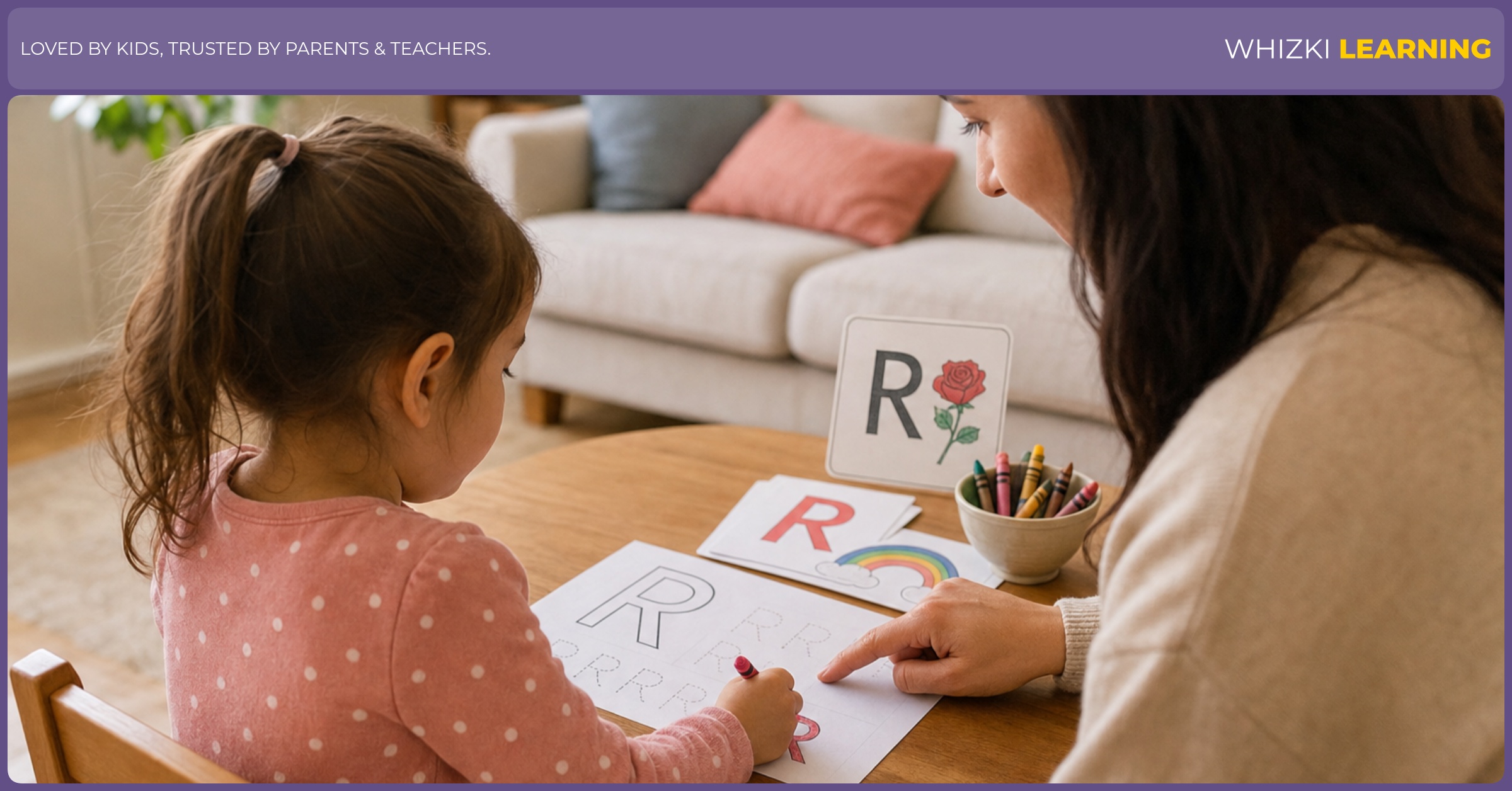 A child traces the letter R with crayons on paper while a parent points to the shape and encourages steady pencil grip