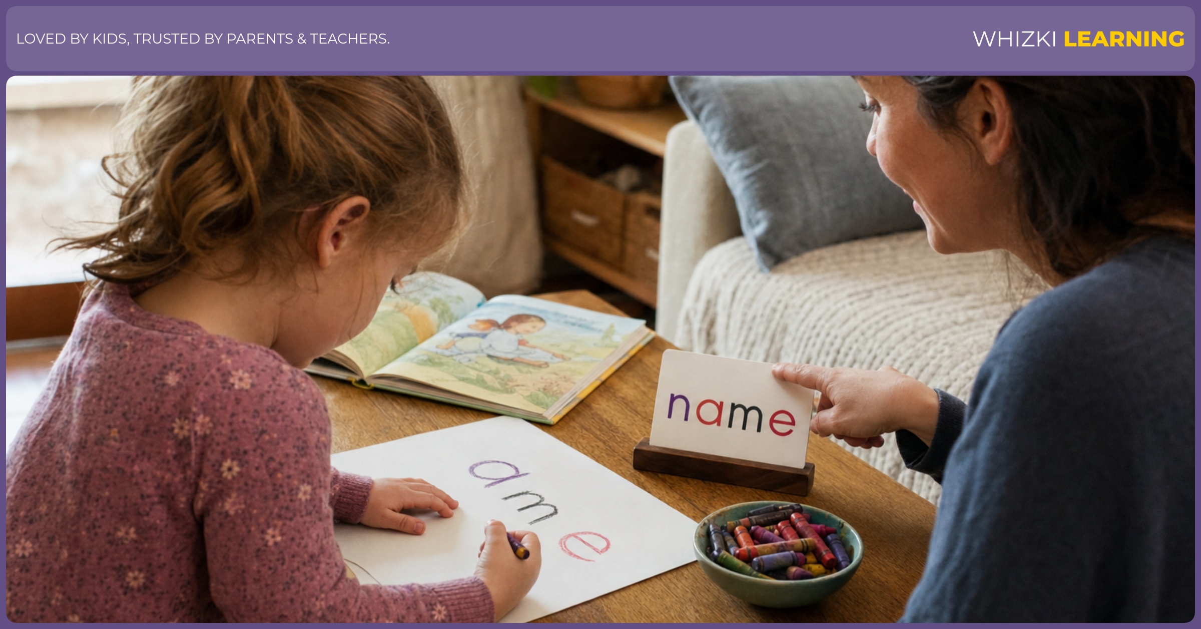 A caregiver sits beside a child practicing lowercase letters in a name with a chunky crayon on paper.