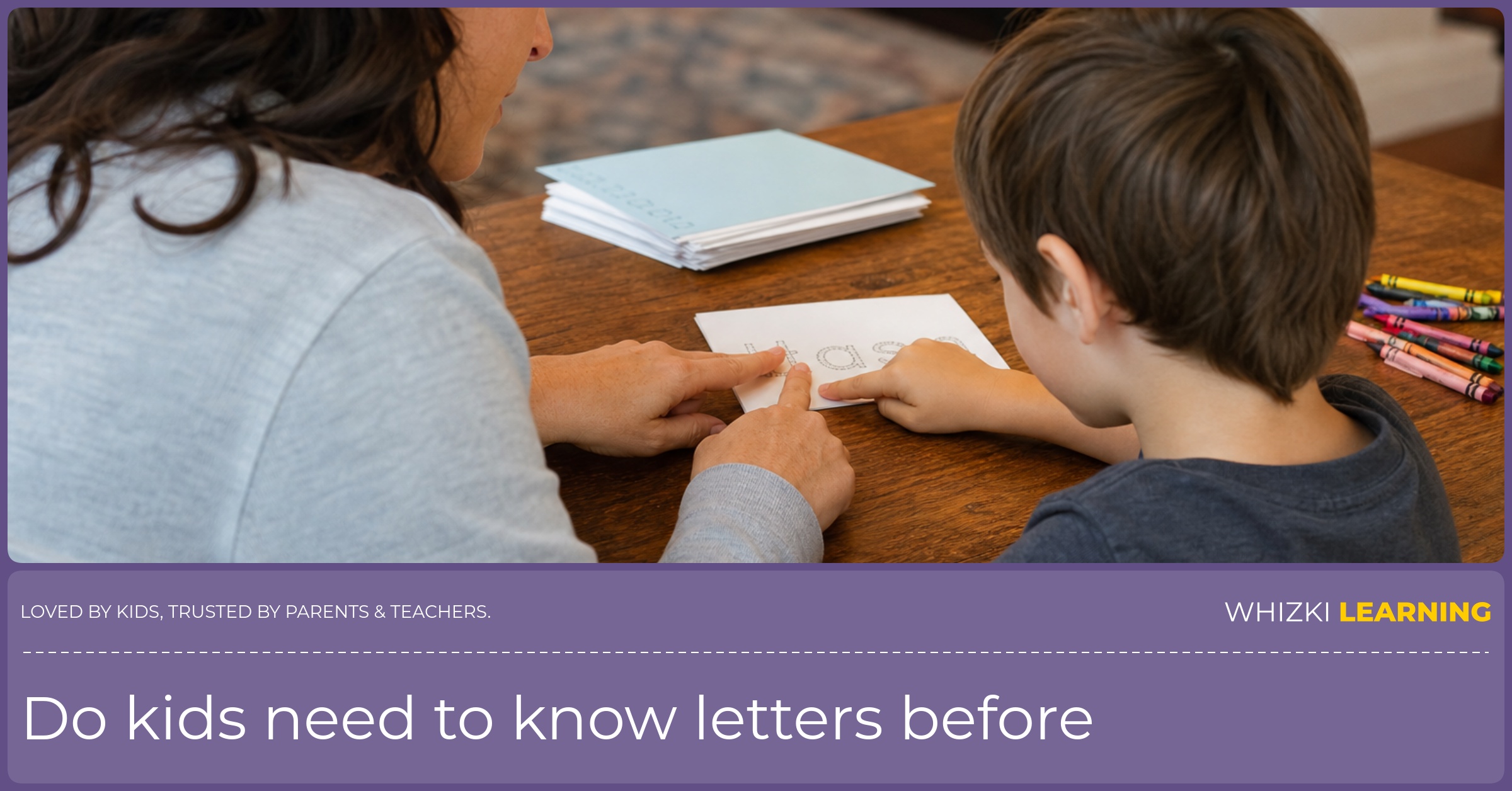 A parent helps a young child trace the first letter of the child's name on a card at the kitchen table.