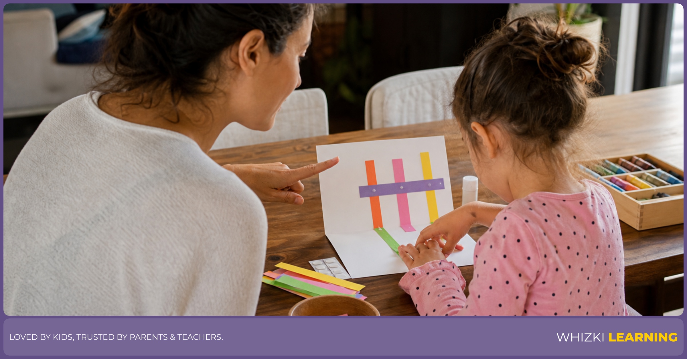 A caregiver and child work through a one-sheet craft circuit with paper strips, glue dots, and folded paper on a warm kitchen table.