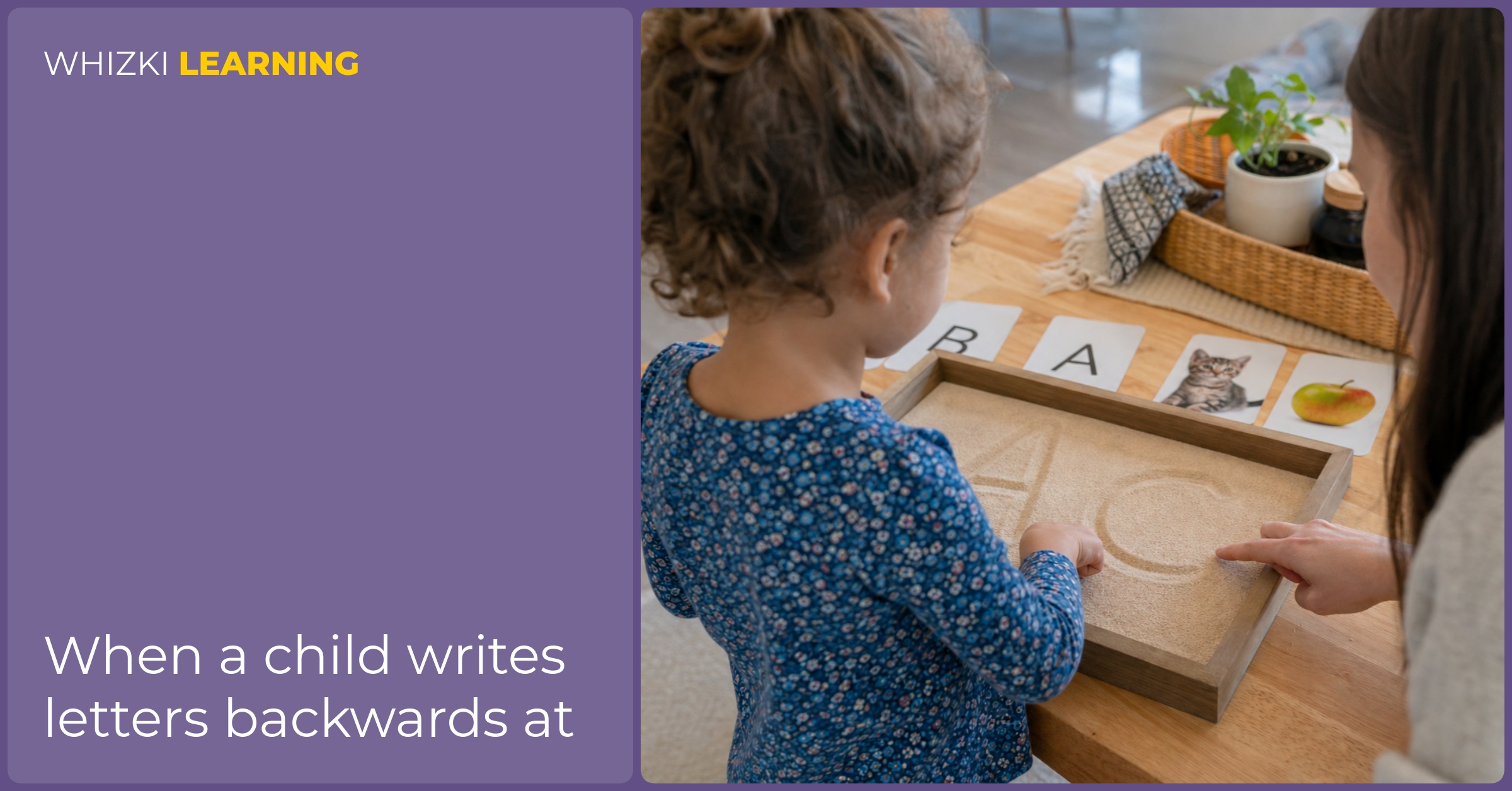 A parent sits beside a young child practicing a letter shape with one finger in a shallow sand tray.