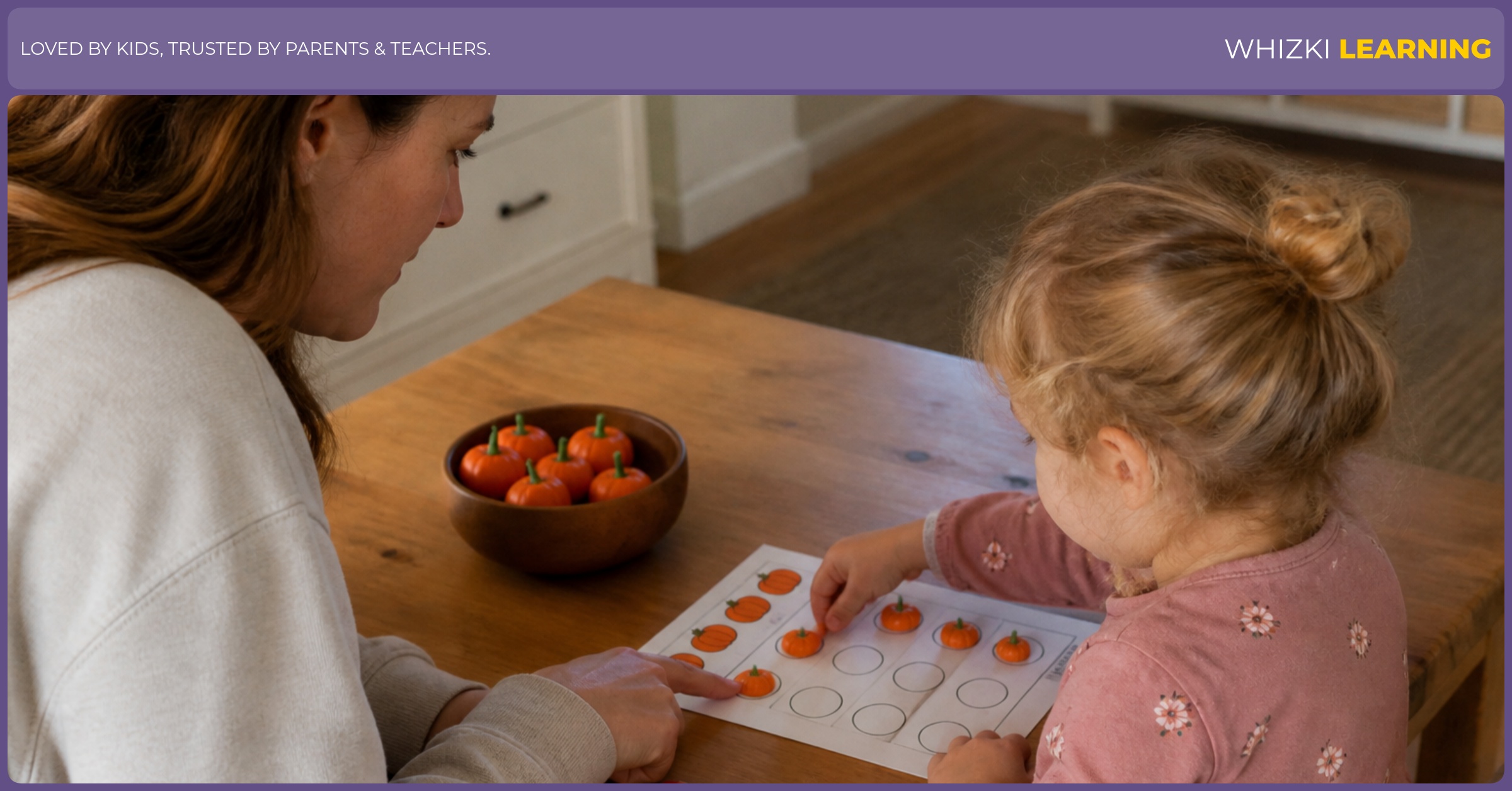 A parent helps a young child count pumpkin counters on a Halloween math worksheet at a kitchen table.