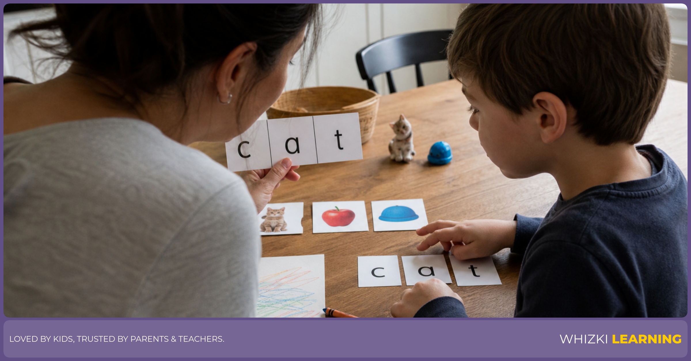 A caregiver helps a child tap sounds with paper letter cards at a kitchen table.
