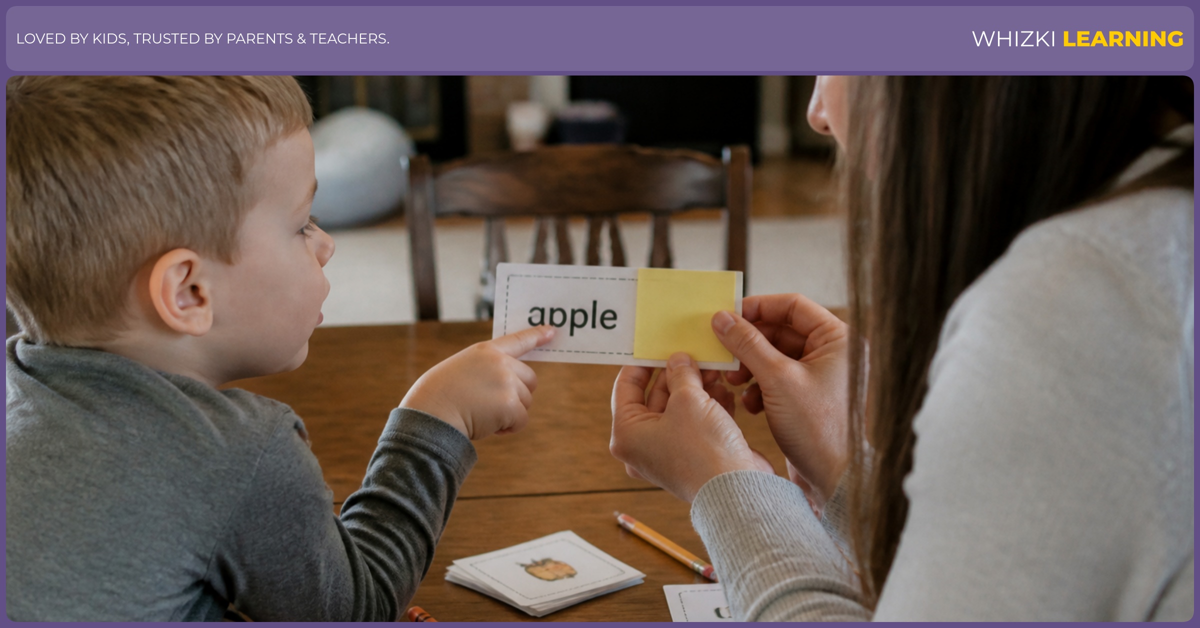 A parent covers the picture on a label card with a sticky note while a young child looks at the word at a kitchen table.