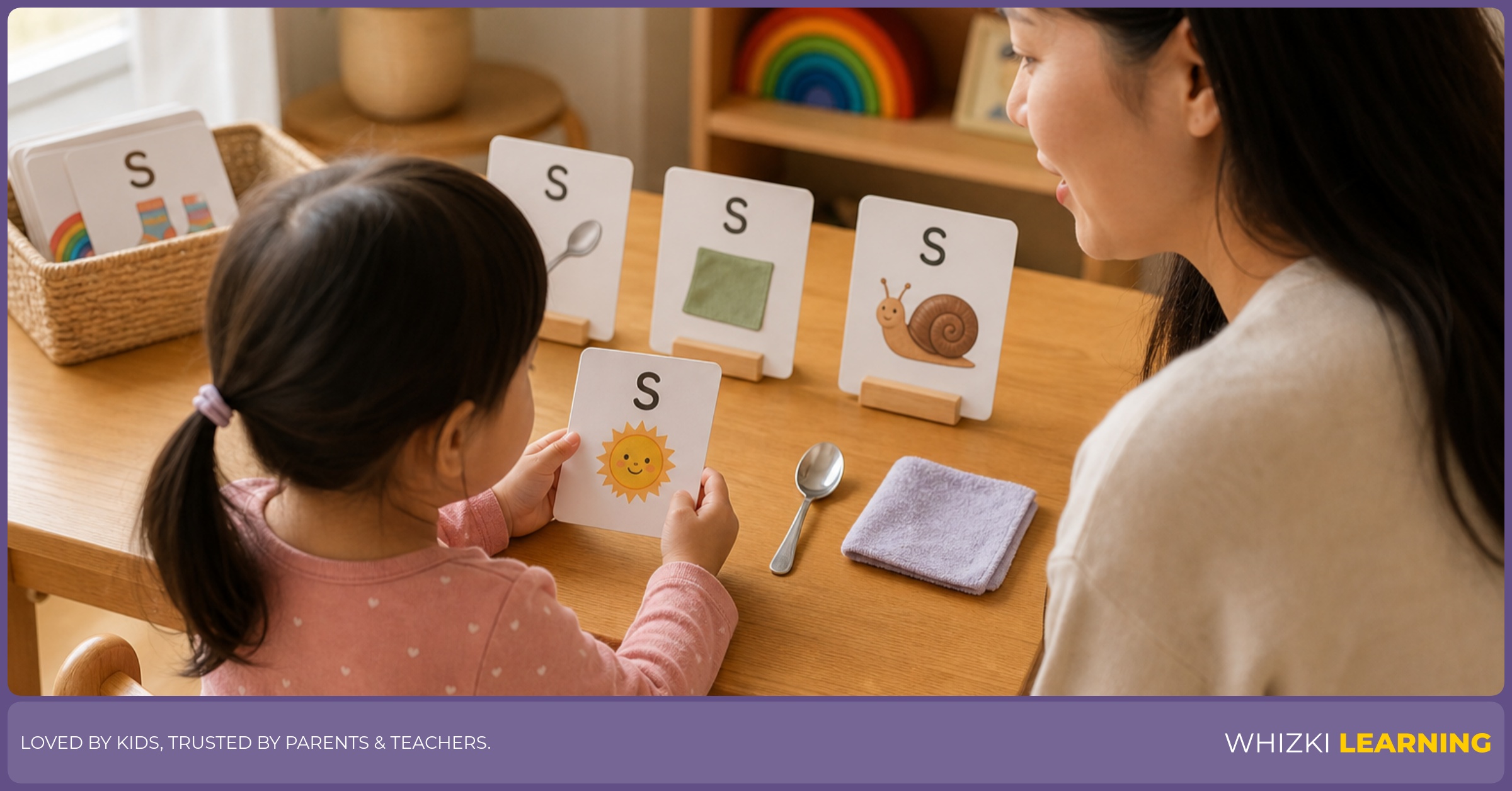 A parent and child compare small and shiny objects while choosing S adjectives, with the child holding the cards toward their own view and the parent speaking softly