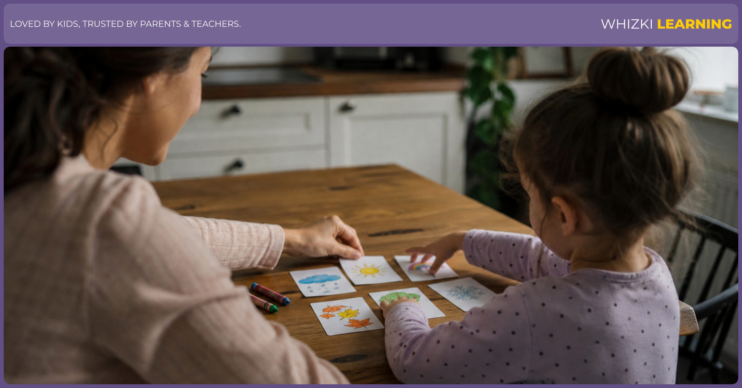 A parent and young child set out hand-drawn picture cards for a German compound word puzzle at a kitchen table.