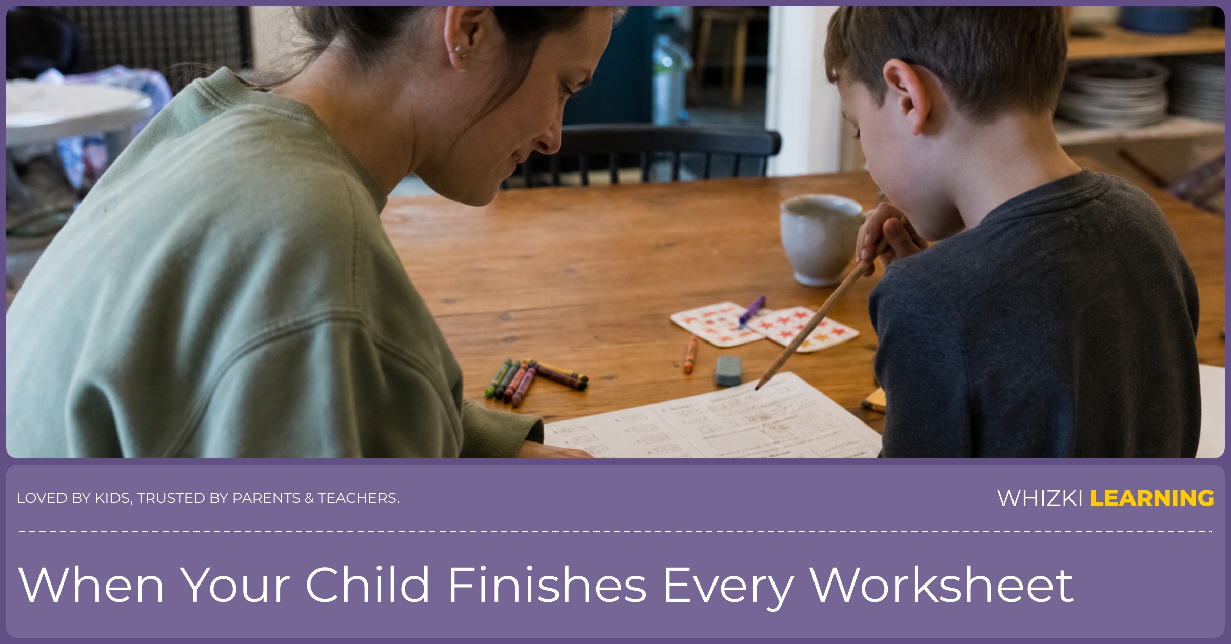 A parent points to a completed worksheet while a young child explains an answer at the kitchen table.
